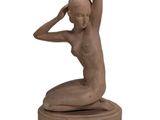 statue of a woman sitting on a base with her hands on her head