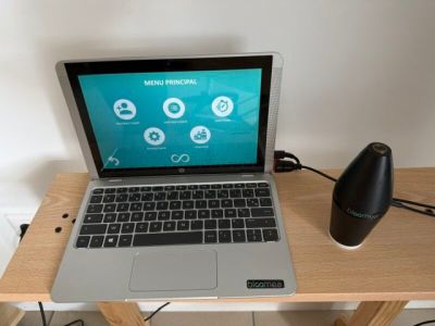 un ordinateur portable posé sur un bureau en bois, avec un haut-parleur