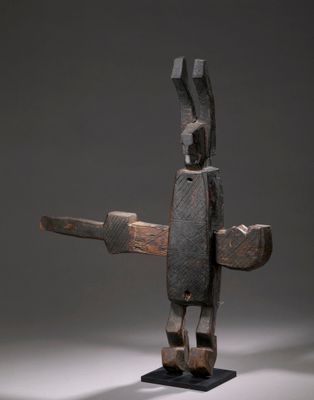 une sculpture en bois représentant une personne tenant un couteau, posée sur une table