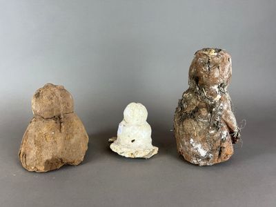 trois animaux en pierre assis les uns à côté des autres sur une surface grise