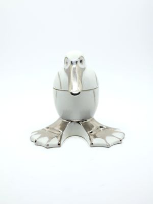 a white bird shaped container with metal feet on a white surface