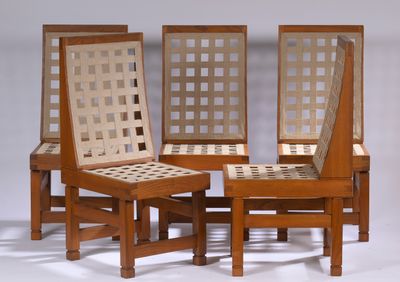 trois chaises en bois aux assises tressées sont alignées sur une surface blanche