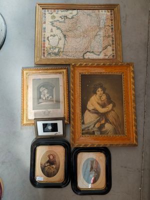 many framed pictures on the wall next to a clock