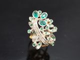 Gros plan sur une bague en or ornée d'émeraudes et de diamants