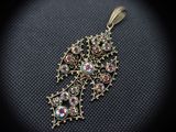 a close up of a gold pendant with colorful stones on it