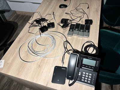 a wooden table with a phone, a telephone, and other electronics on it