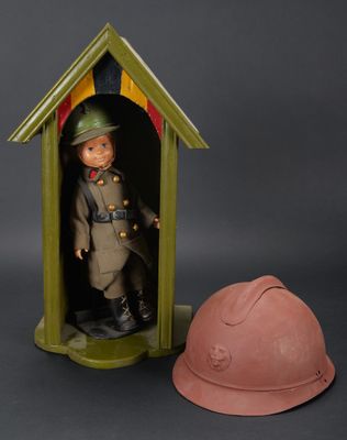 un petit soldat dans une serre, avec un casque à côté de lui