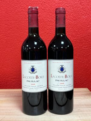 two bottles of red wine sit on a table in front of a red wall