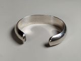 silver cuff bracelet with curved design on a white surface
