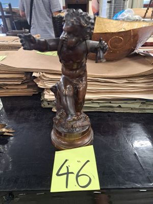 une statue représentant un garçon tenant un panier posé sur une table