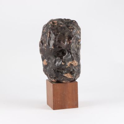 une image représentant une sculpture représentant une tête d'homme posée sur un socle en bois