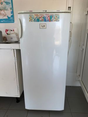 a small white refrigerator in a kitchen with tile flooring