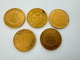 four gold coins sitting on top of each other on a white surface