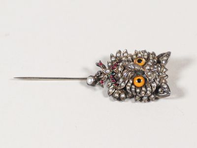 une image représentant une broche en forme de chouette avec des yeux jaunes sur la tête