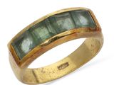 Gros plan sur une bague en or ornée de pierres vertes