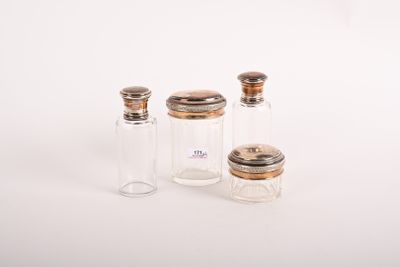 trois petites bouteilles en verre avec des bouchons argentés, posées sur une surface blanche