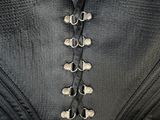 the back of a black corset with silver buttons on it