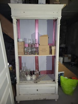 Une armoire bonnetière peinte en blanc, manquant de porte.