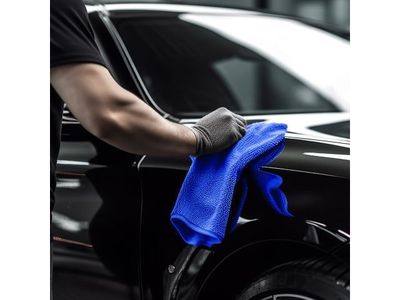 un gros plan d'une personne en train de nettoyer une voiture avec une serviette bleue