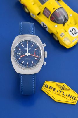 une montre posée à côté d'une petite voiture sur une table bleue