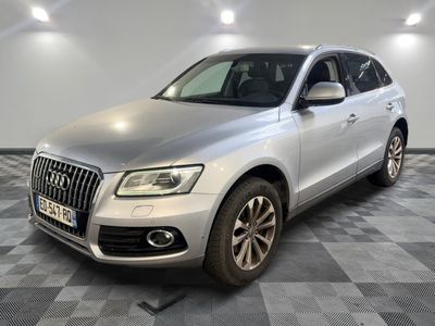 une Audi QX argentée garée sur un sol en carrelage à damier