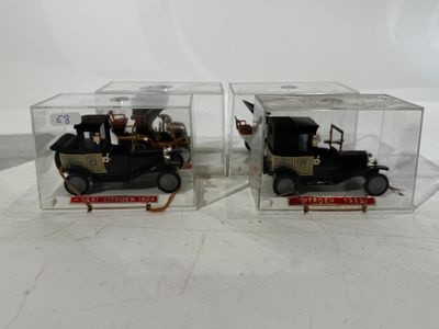 pair of antique model cars in clear boxes on white surface