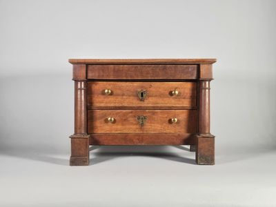 une petite commode en bois comportant trois tiroirs d'un côté et deux de l'autre