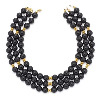 un collier de perles noires rehaussé de touches dorées sur fond blanc