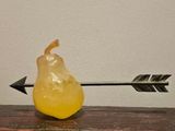 a pear with an arrow stuck in it on a table