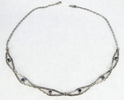 silver necklace with blue stones and silver chain on white background