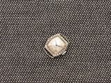 un gros plan d'une bague sertie d'un diamant, posée sur un tissu