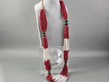 collier de perles rouges et blanches sur un mannequin tenant une boule de verre