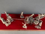a silver model of a horse drawn carriage with people on it