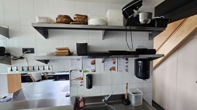 a kitchen with a sink, stove, and shelves in it
