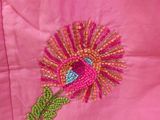 embroidered flower on a pink jacket with green leaves on it