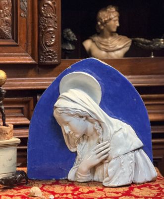une statue représentant une femme tenant un bébé dans ses bras, à côté d'une plante en pot