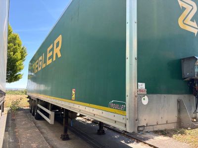 un semi-remorque vert garé sur le bord de la route