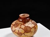 a small vase with a design on it on a white surface