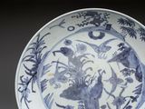 a blue and white plate with birds and flowers on it