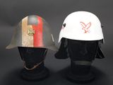 two helmets with red and white stripes on them sitting on top of a mannequin head