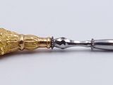 a silver and gold object on a white surface