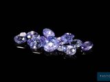 a bunch of purple sapphires sitting on top of a black surface
