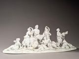 a white sculpture of a group of people on a table