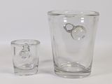 a glass vase and a shot glass sitting on a table