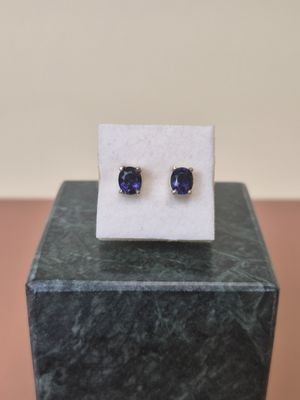 a pair of blue sapphire earrings sitting on top of a marble block
