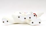 a white cat figurine that is laying down on the ground