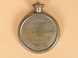 a silver pocket watch on a beige surface