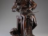 statue en bronze représentant un homme assis sur un tabouret, coiffé d'un chapeau