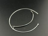 un gros plan sur une paire de boucles d'oreilles créoles argentées posées sur une surface noire