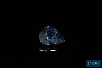 a close up of a blue diamond on a black surface